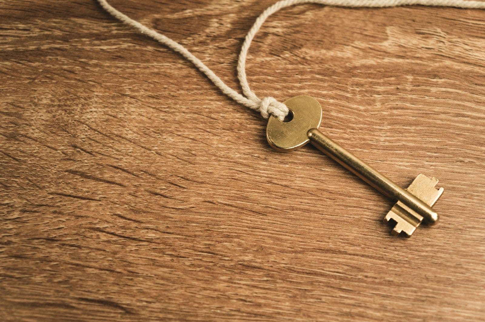 Brass key on a string resting on a wooden table