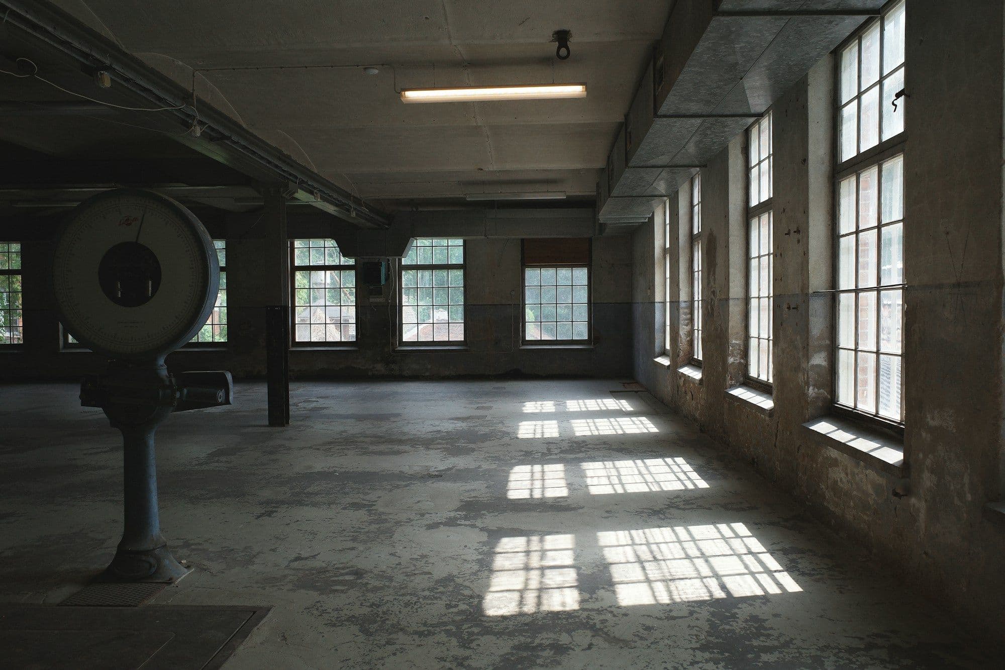 Empty factory floor with an old industrial scale and sunlight through tall windows
